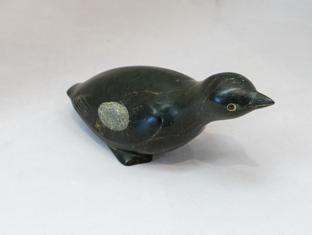 Dark stone carved bird with pointy beak. 