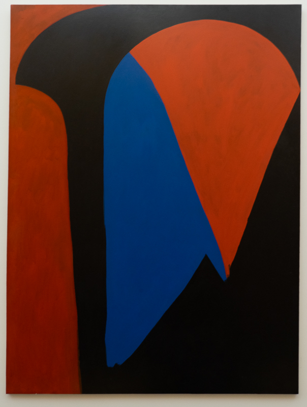 Irregular geometric form in black with blue and orange insets on a red background.